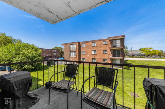 View from a balcony overlooking a brick apartment building and a grassy area.