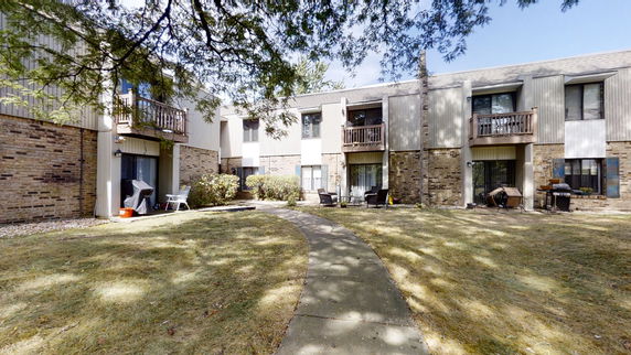 Exterior view of a multi-story residential building with balconies and a pathway leading to the entrance.