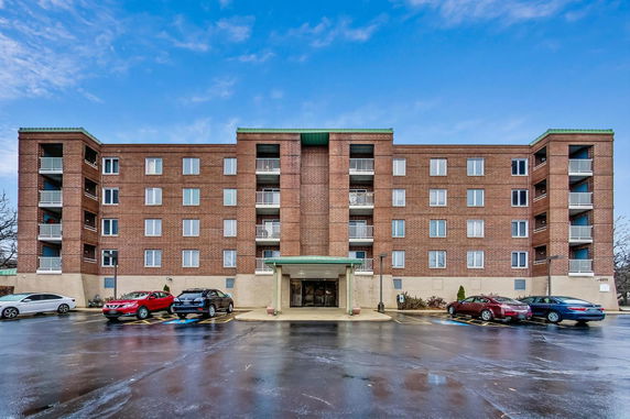 Front view of a five-story apartment building with a parking area.