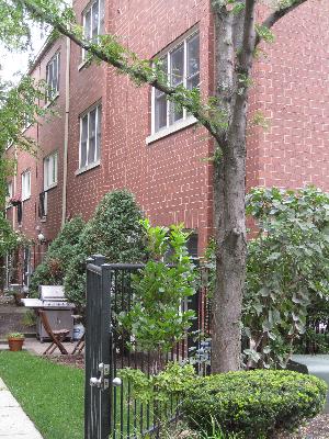 Side view of a brick residential building with multiple floors and a small gate entrance.
