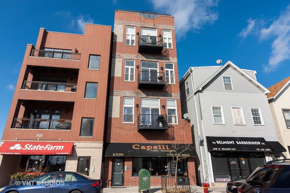 Front view of multi-story brick and siding buildings with retail shops on the ground floor.