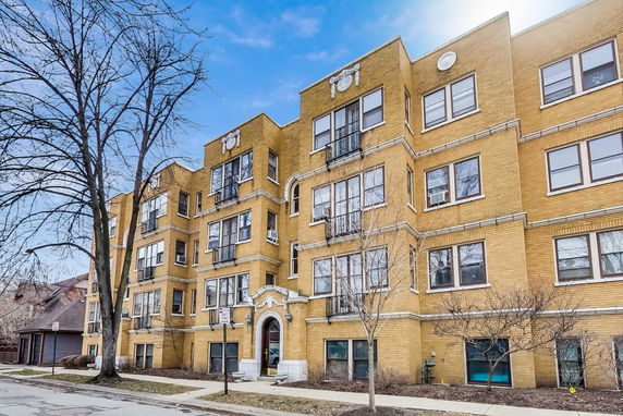 Front view of a multi-story brick apartment building with decorative elements above windows.