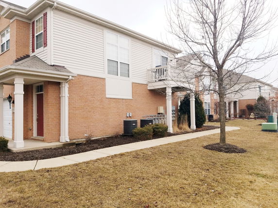 Front view of a two-story house with a small balcony and brick exterior.