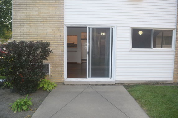 Exterior view of a house with brick and siding, featuring a sliding glass door.