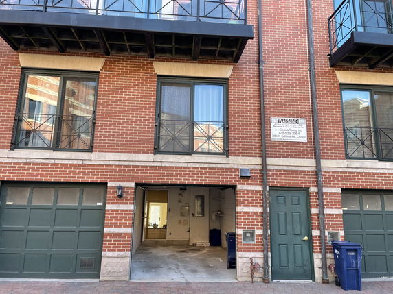 Front view of a multi-story brick building with garage and door entrances.