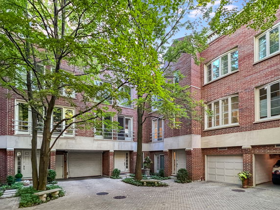 Front view of a multi-story residential building with brick facade and multiple garages.
