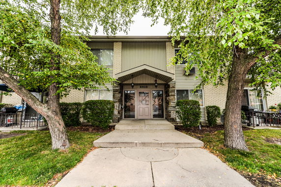 Front view of a two-story residential building with brick facade and trees in front.