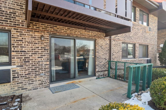 Front view of a brick building with a sliding glass door and a balcony above.