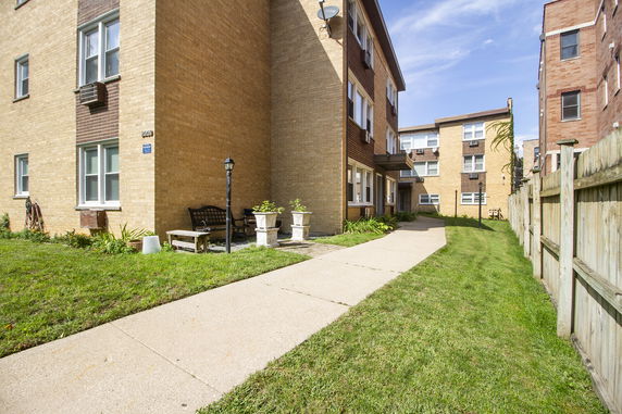 Front view of adjacent residential brick buildings with windows and a walkway.