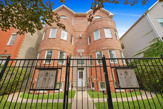 Front view of a brick multi-story building with symmetrical design and multiple windows.