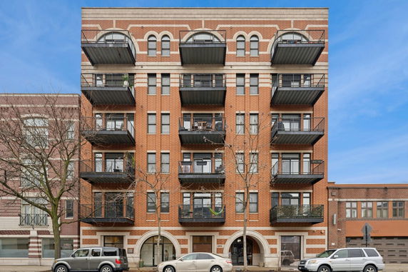Front view of a multi-story brick apartment building with balconies.