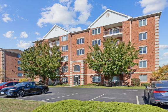 Front view of a multi-story brick building with a parking area.