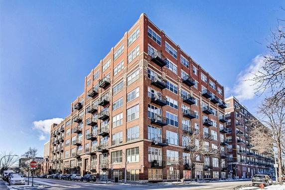 Front view of a multi-story brick apartment building with balconies.