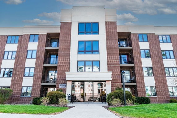 Front view of a multi-story apartment building with brick facade and large windows.
