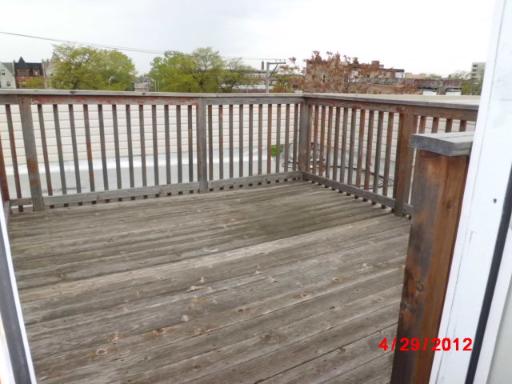 Rooftop view with wooden flooring and railing.
