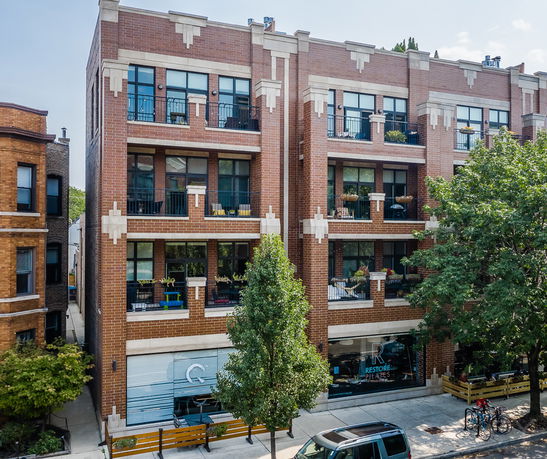 Front view of a multi-story brick apartment building with balconies.