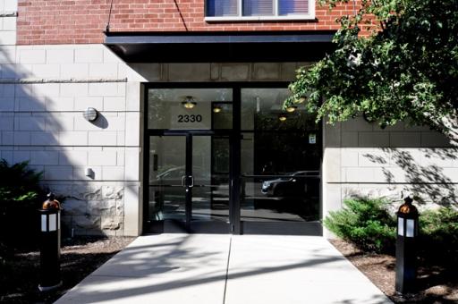 Front view of a building entrance with glass doors and a brick facade.