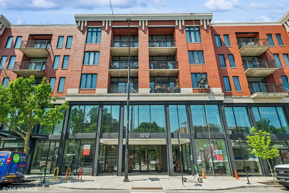 Front view of a multi-story building with balconies and large glass entrance.