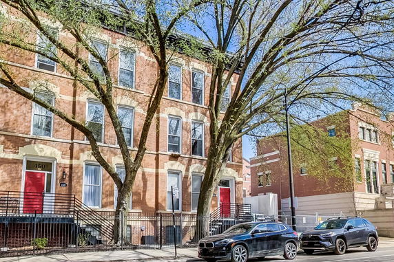 Front view of a multi-story brick building with red doors.