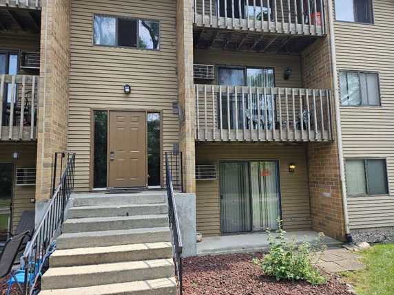 Front view of a multi-story apartment building with balconies and a central entrance.