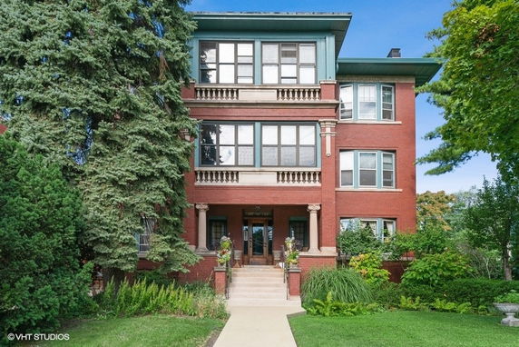 Front view of a three-story brick building with large windows and decorative columns.