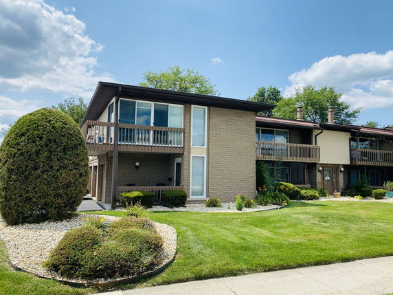 Front view of a two-story house with a balcony and large windows.
