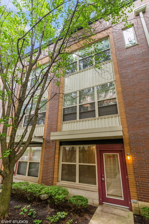 Front view of a multi-story brick building with large windows and a red entrance door.