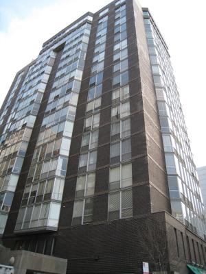 Front view of a tall multi-story building with numerous windows and brick facade.