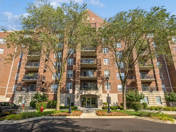 Front view of a multi-story brick apartment building with balconies.