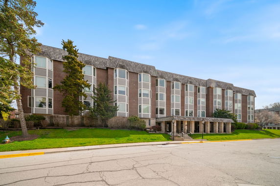 Front view of a multi-story brick building with large windows and a covered entrance.