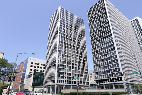 Front view of two modern high-rise buildings with grid-like window patterns.