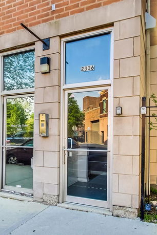 Front view of a building entrance with a glass door and brick facade.
