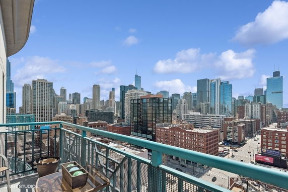Panoramic view of a city skyline from a balcony, featuring numerous skyscrapers and buildings.