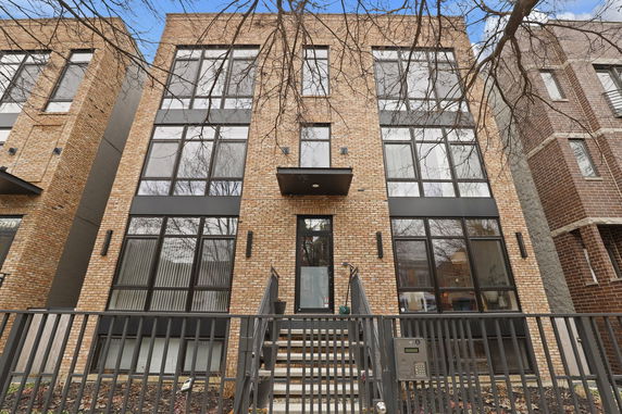 Front view of a modern multi-story building with brick facade and large windows.