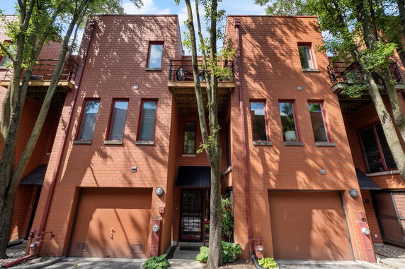 Front view of a brick townhouse with multiple stories and garages.