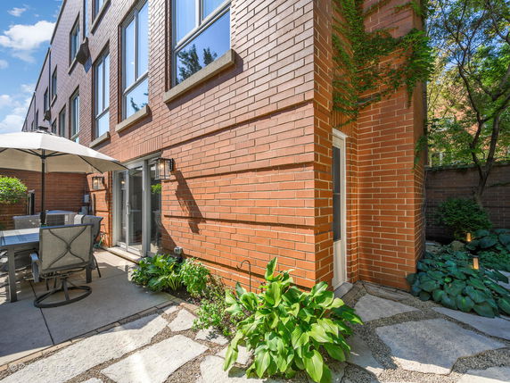 Front view of a multi-story brick house with large windows and a patio area.
