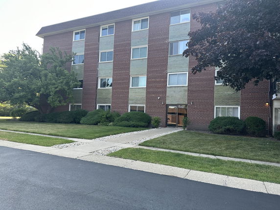 Front view of a four-story brick apartment building with multiple windows.