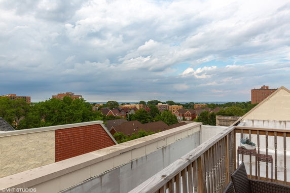 Panoramic view from a rooftop overlooking a neighborhood with houses and buildings.