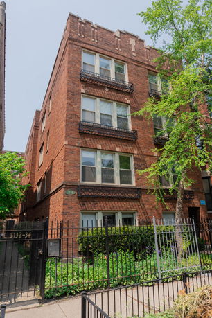 Front view of a multi-story brick building with multiple windows and balconies.
