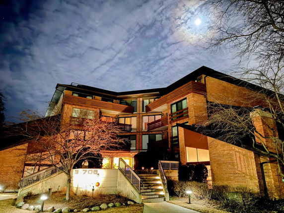Front view of a multi-story building with brick exterior and multiple balconies, illuminated at night.