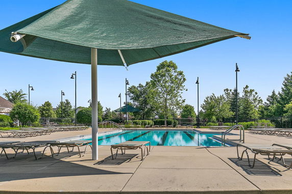 Outdoor swimming pool with surrounding deck chairs and shade umbrellas.
