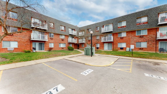 Front view of a multi-story brick apartment building with balconies.