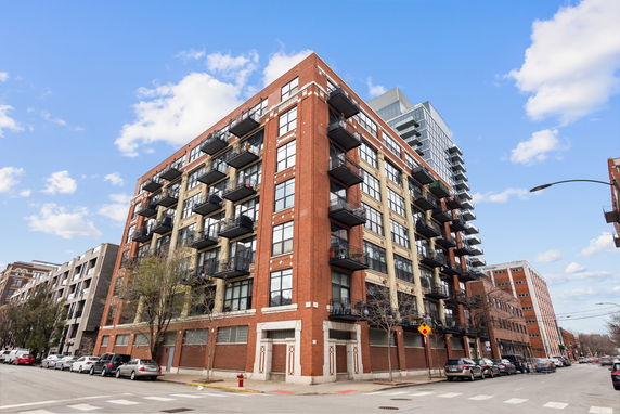 Front view of a multi-story brick apartment building with balconies.
