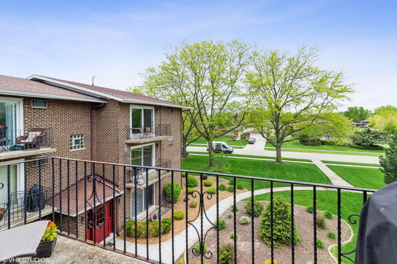 Wide angle view from a balcony overlooking a residential area with brick buildings and green lawns.