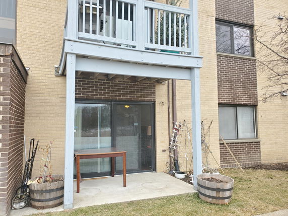 Rear view of a multi-story building with balcony and patio area.