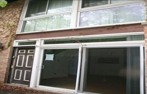 Front view of a two-story building with large windows and a sliding glass door.