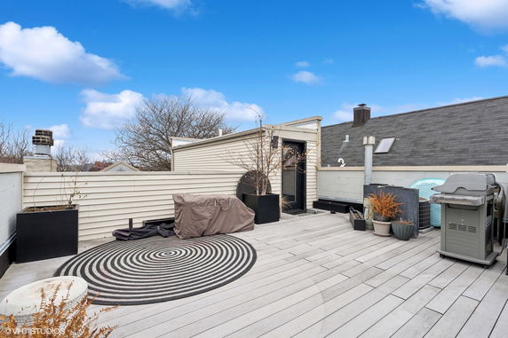 Rooftop area with wooden decking, a covered grill, and planters.