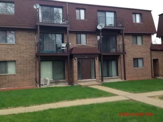 Front view of a multi-story apartment building with balconies and brick exterior.
