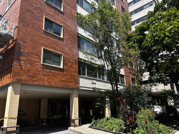 Front view of a multi-story brick apartment building with a sheltered entrance.