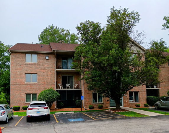 Front view of a three-story brick apartment building with balconies.